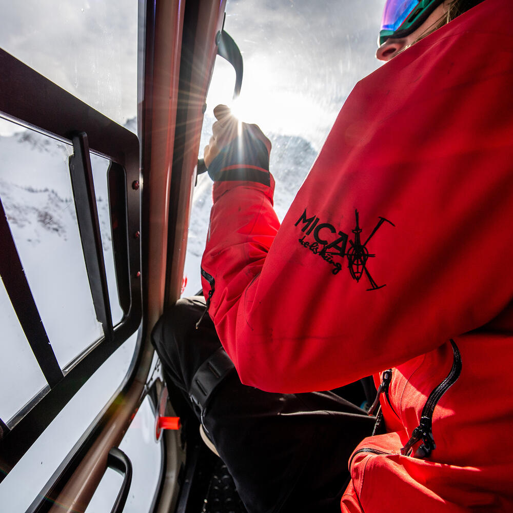A Heliski Guide sitting in a helicopter in a red jacket looking out the window